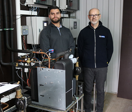 Michael and Abdallah in front of a heat pump